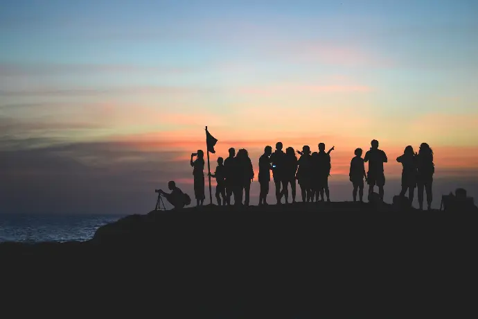 silhouette photography of people gathered together on cliff